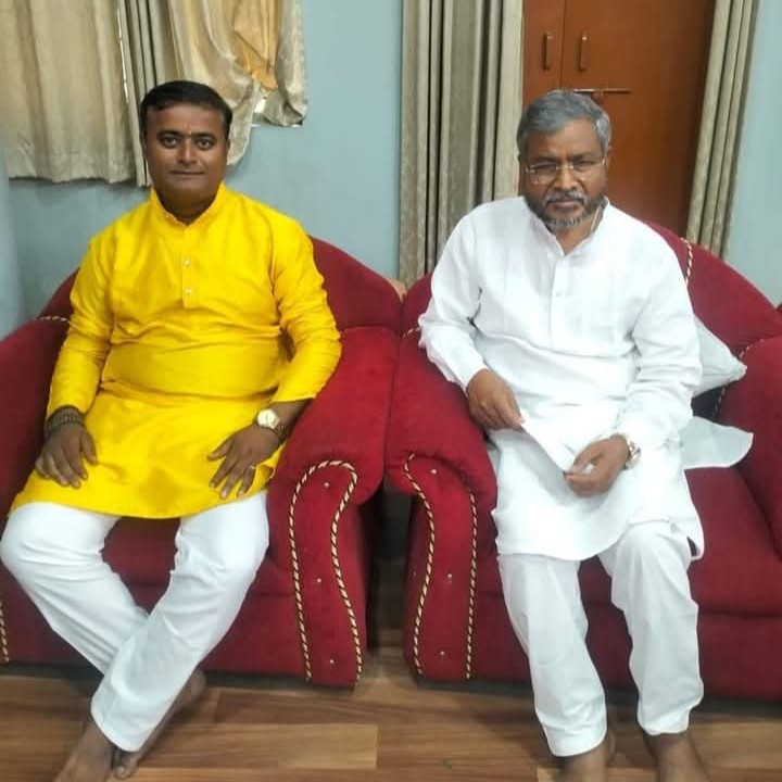A man in a yellow kurta seated on a red sofa next to Babulal Marandi
